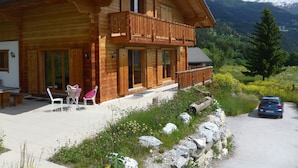A wooden chalet with a balcony, a covered patio, and a stone wall. - Crans Montana - Large and modern chalet with stunning views in a quiet setting (Randogne)