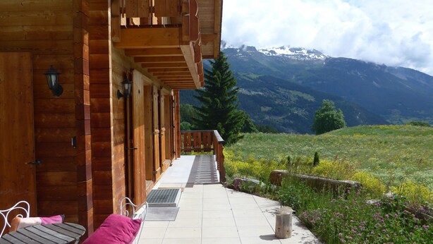 A wooden building with a covered outdoor area, a bench, and a view of mountains. - Crans Montana - Large and modern chalet with stunning views in a quiet setting (Randogne)