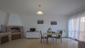 A spacious living area with a fireplace, a dining table with chairs, a television, and two paintings on the wall. - "Between Norba and Norma" cozy apartment (Norma)