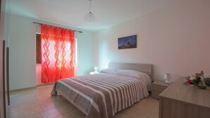 A bedroom with a bed, a nightstand, a desk, a chair, a window with curtains, and a painting on the wall. - "Between Norba and Norma" cozy apartment (Norma)