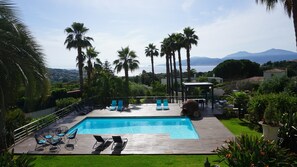 A pool area with lounge chairs, a wooden deck, and a view of the sea and mountains. - Splendid estate with 3 villas with sea and pool views in Porticcio (Grosseto-Prugna)
