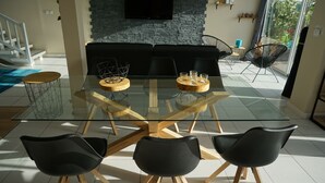 Ein moderner Essbereich mit einem Glastisch, Holzstühlen und einer Wand aus Stein mit einem Fernseher.