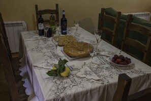 A dining table set with a bread basket, wine bottles, glasses, and a bowl of fruit. - Tranquility, friendship and good times. (Sotoserrano)