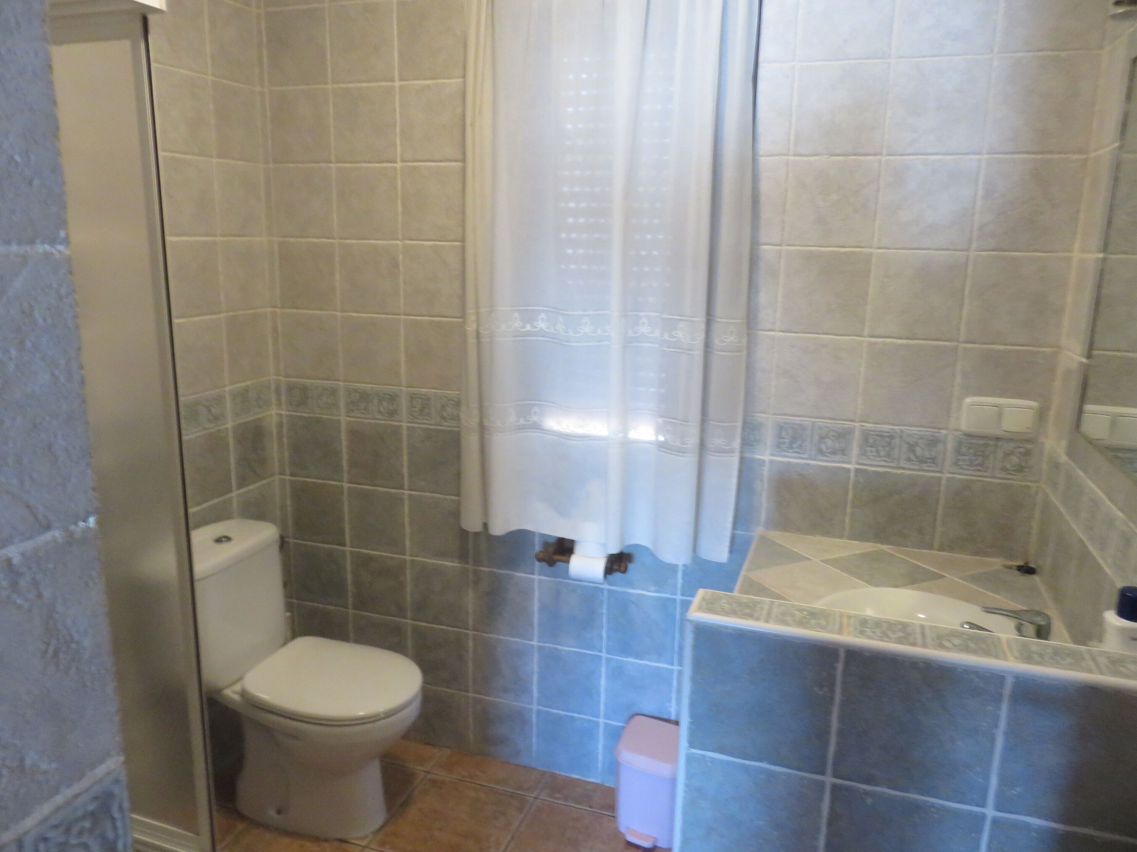 A bathroom with a toilet, a shower with a glass door, and a sink with a mirror.