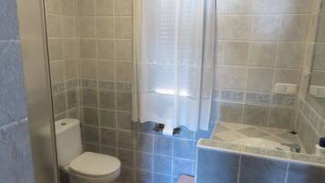 A bathroom with a toilet, a shower with a glass door, and a sink with a mirror.