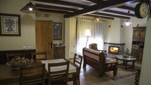 Un salon chaleureux avec une cheminée, des meubles en bois et un coin repas comprenant une table et des chaises.