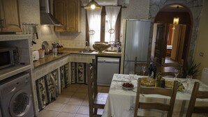 Une cuisine compacte équipée d’un lave-linge, d’un évier et d’un coin repas avec une table dressée pour deux personnes.