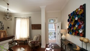 A living room with a wooden floor, a chandelier, a sofa, a coffee table, and a wall art piece made of painted cans. - A spacious and luxurious three-bedroom house with courtyard and roof deck (Cape Town)