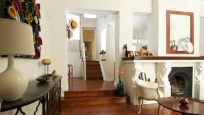 A spacious living room with a wooden staircase, a fireplace, and a variety of decorative items. - A spacious and luxurious three-bedroom house with courtyard and roof deck (Cape Town)