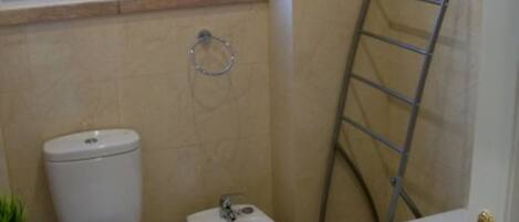 Une salle de bain comprenant des toilettes, un bidet, un lavabo et une baignoire.
