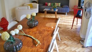 Una sala de estar con una mesa de comedor de madera, dos sofás, un televisor y un ventilador.