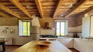 Une cuisine spacieuse dotée d’un grand îlot central en bois, d’un four encastré et d’une fenêtre laissant entrer la lumière naturelle.
