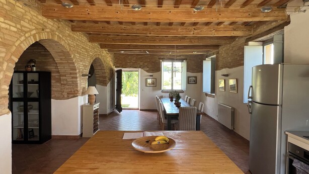 Une cuisine spacieuse avec une table en bois, un réfrigérateur et une fenêtre.