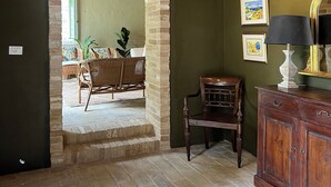 Une pièce avec une arche en briques donnant sur un coin repas, un meuble en bois et une lampe.