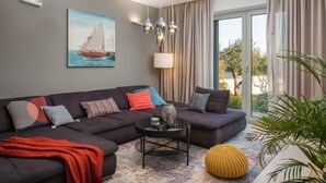 A modern living room with a sectional sofa, a coffee table, and a large window with curtains. - Luxury Villa Cinderella with Swimming Pool (Primošten)