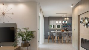 A modern living room with a TV, a large plant, and a dining area with a kitchen in the background. - Luxury Villa Cinderella with Swimming Pool (Primošten)