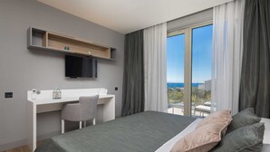 A modern hotel room with a bed, a desk, a chair, a TV, and a balcony with a view. - Luxury Villa Cinderella with Swimming Pool (Primošten)