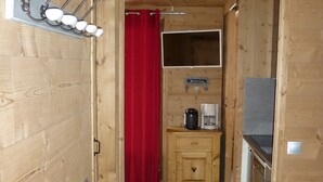 Un interior de madera con kitchenette, una cortina roja y un accesorio de iluminación instalado.