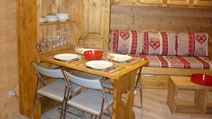 Una mesa de comedor de madera con sillas, un cuenco rojo y un armario de madera con estantes.