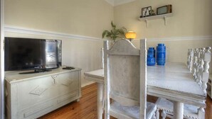 Una habitación con televisor sobre un tocador, una lámpara y una mesa con recipientes azules.