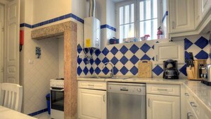 Una cocina con armarios blancos, lavavajillas, estufa y cafetera.