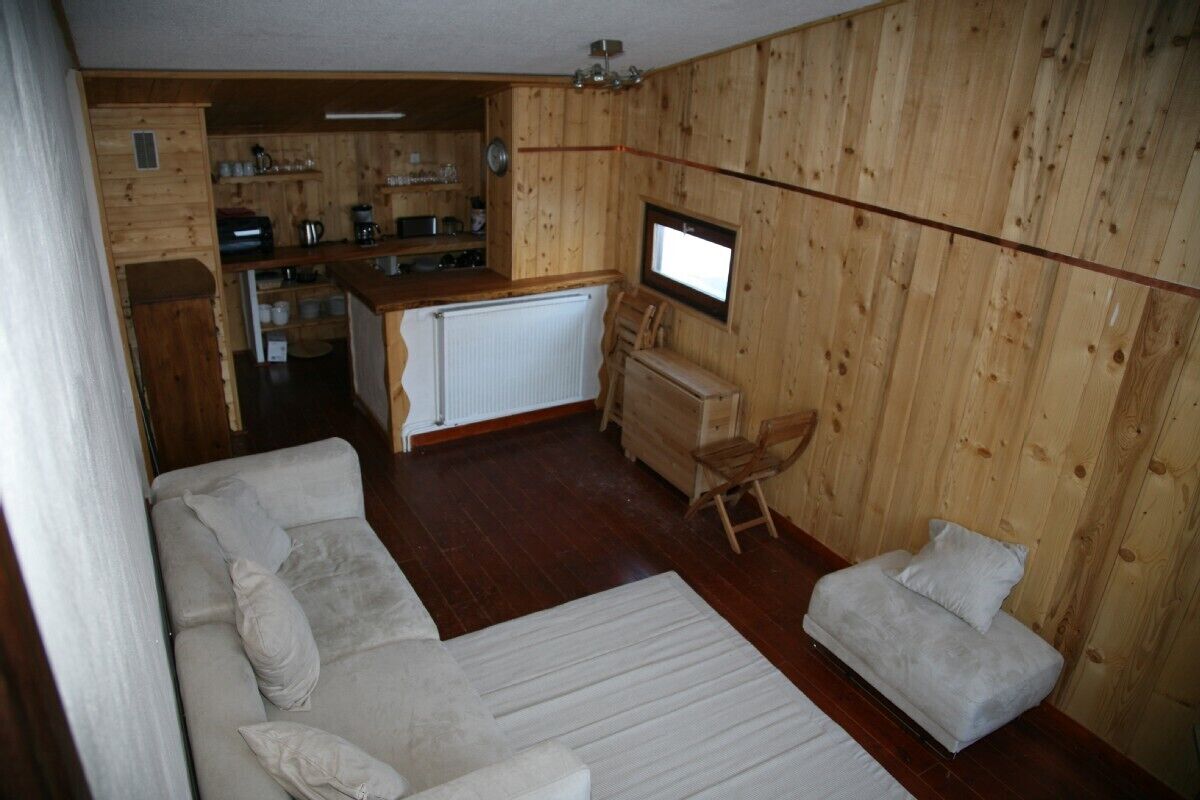 Una habitación compacta con sofá, una mesita y un pequeño espacio con cocina.