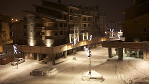 Une rue enneigée bordée d’immeubles, dont un hôtel doté de balcons et d’une enseigne indiquant « Maison de Tignes ».