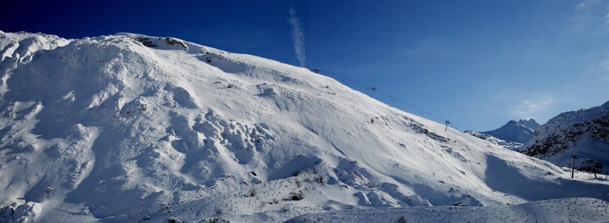 A snow-covered mountain slope with a clear sky.