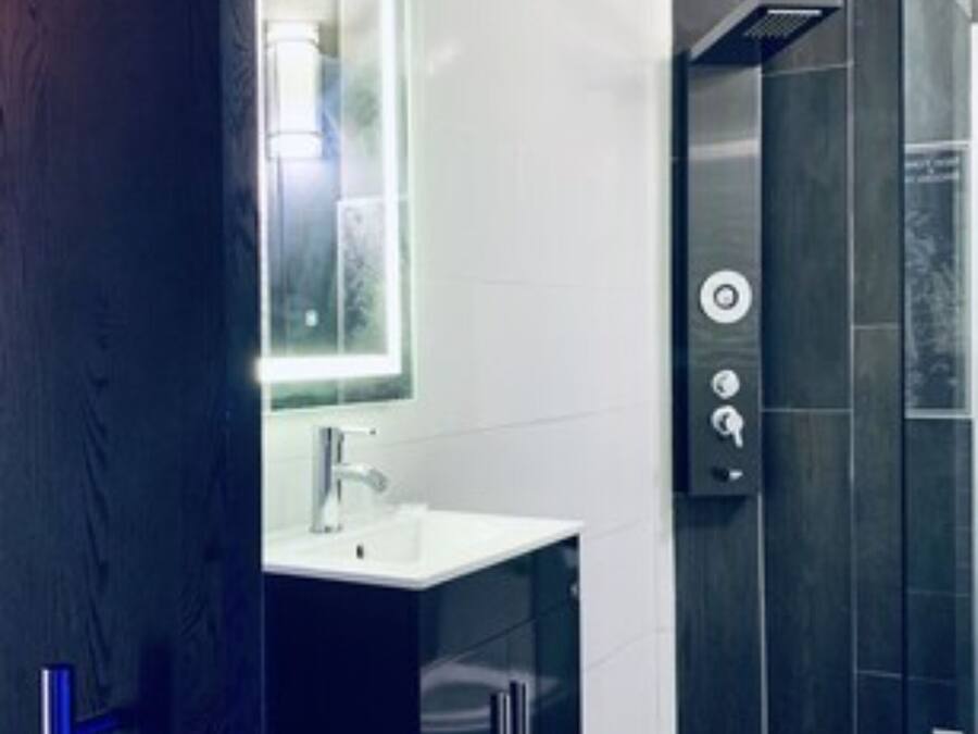 A modern bathroom with a glass shower enclosure, a white sink, and a dark-toned vanity.