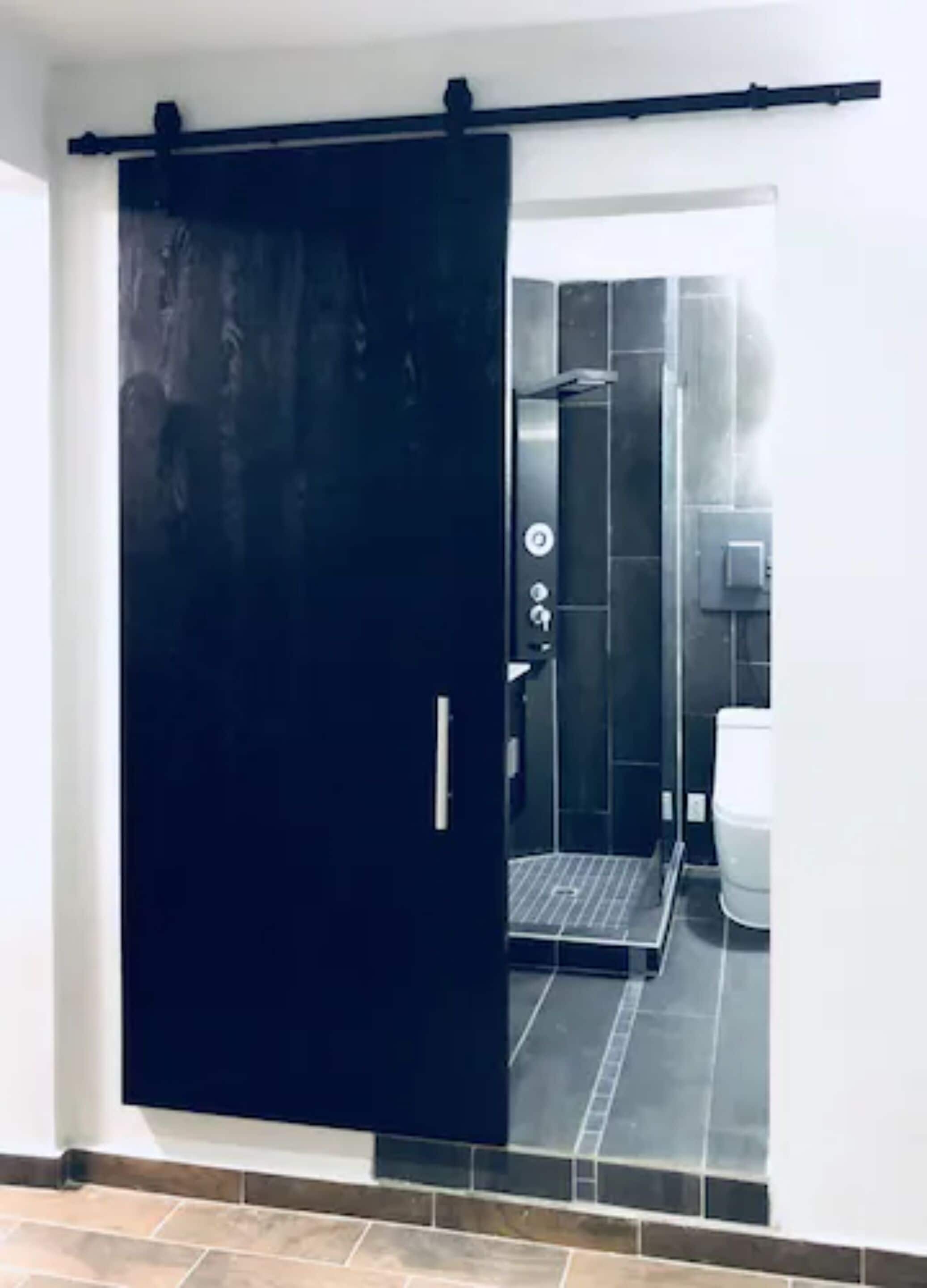 A modern bathroom with a shower, toilet, and a glass partition.