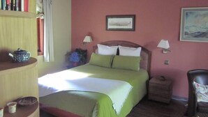 A bedroom with a bed, bedside lamps, a bookshelf, a window with curtains, and a painting on the wall.