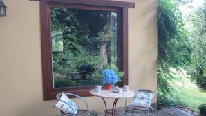 A patio with two chairs, a table, and a window overlooking a garden.