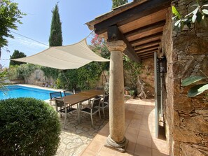 A poolside area with a stone wall, a wooden pergola, and a table with chairs. - Holiday rental villa with swimming pool in Begur, Casa de Campo (Begur)