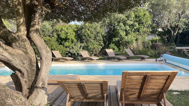 A wooden deck with lounge chairs facing a swimming pool, surrounded by lush greenery. - 
Private villa  and large  pool 08 mn from Porto Vecchio and marvellous beaches
 (Porto-Vecchio)