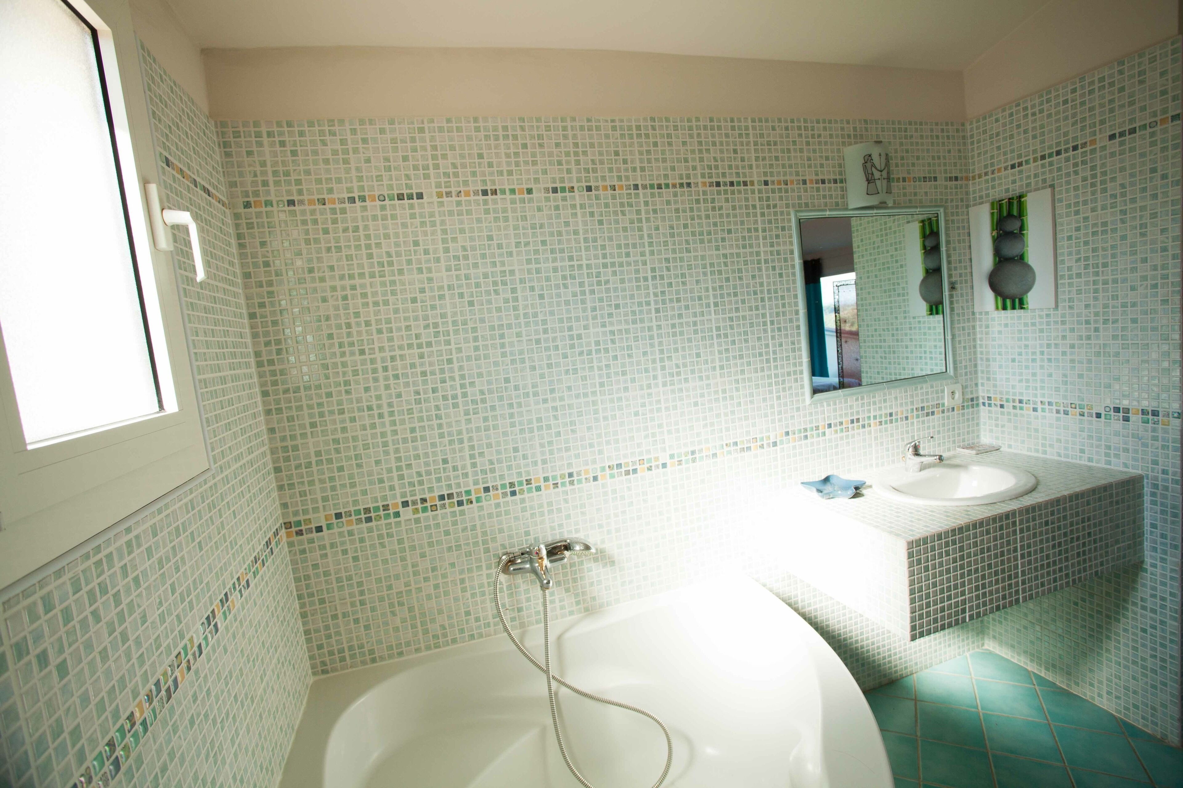 A bathroom with a bathtub, a sink, and a mirror.