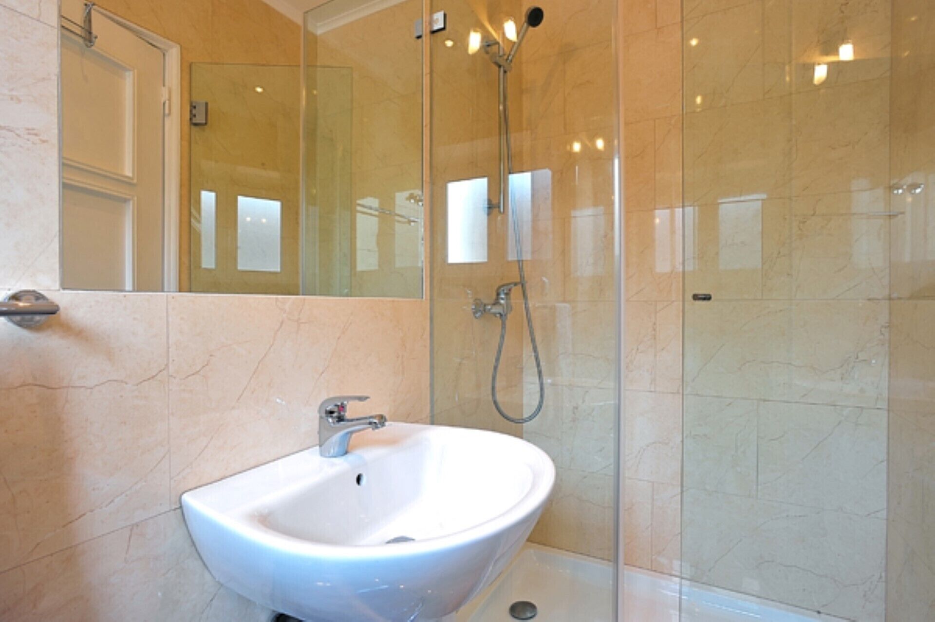 A bathroom with a white sink, a glass shower enclosure, and a mirror.
