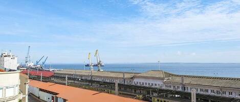 A coastal industrial area with shipping cranes, a port, and a building with a red roof.