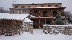 A two-story stone building with a balcony, surrounded by snow.