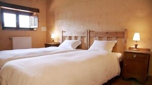 A double room with two beds, wooden headboards, and bedside lamps.