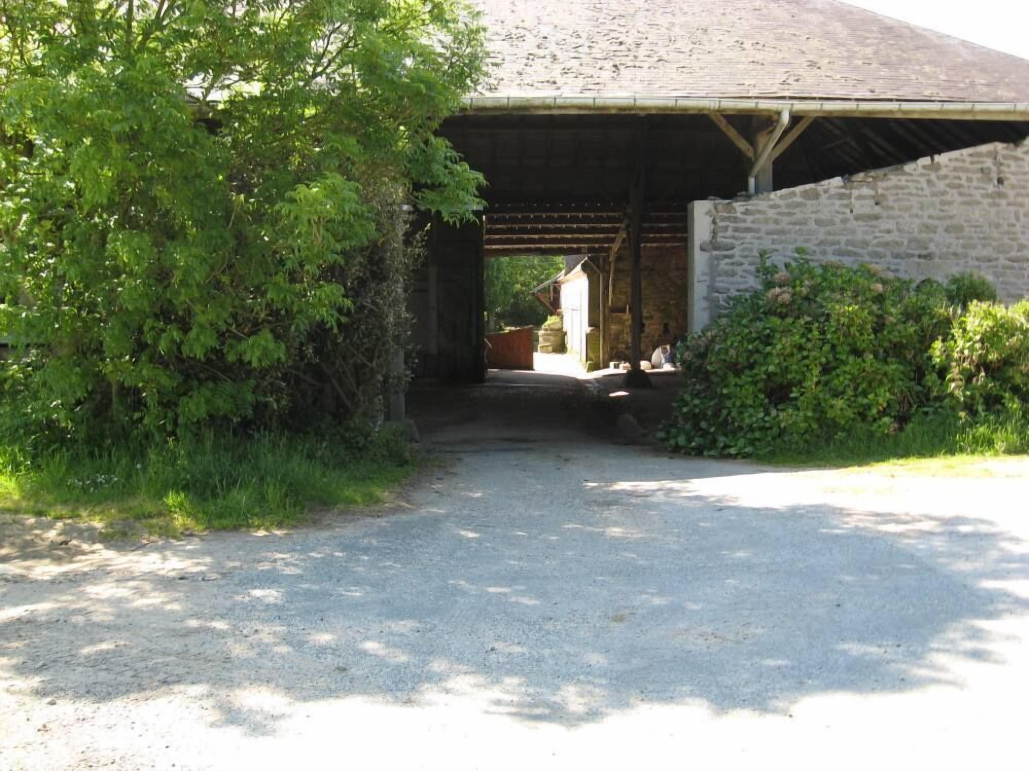 A rustic stone building with a covered entrance and a gravel path leading to it.