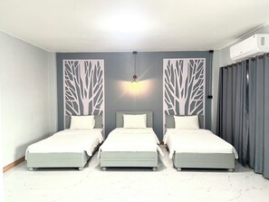 Een kamer met drie op rij staande bedden, een plafondlamp en een luchtverwarmer aan de muur.