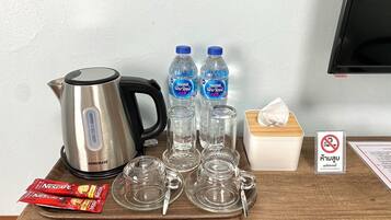 A kitchen setup with a kettle, water bottles, a tissue box, and Nescafe packets.