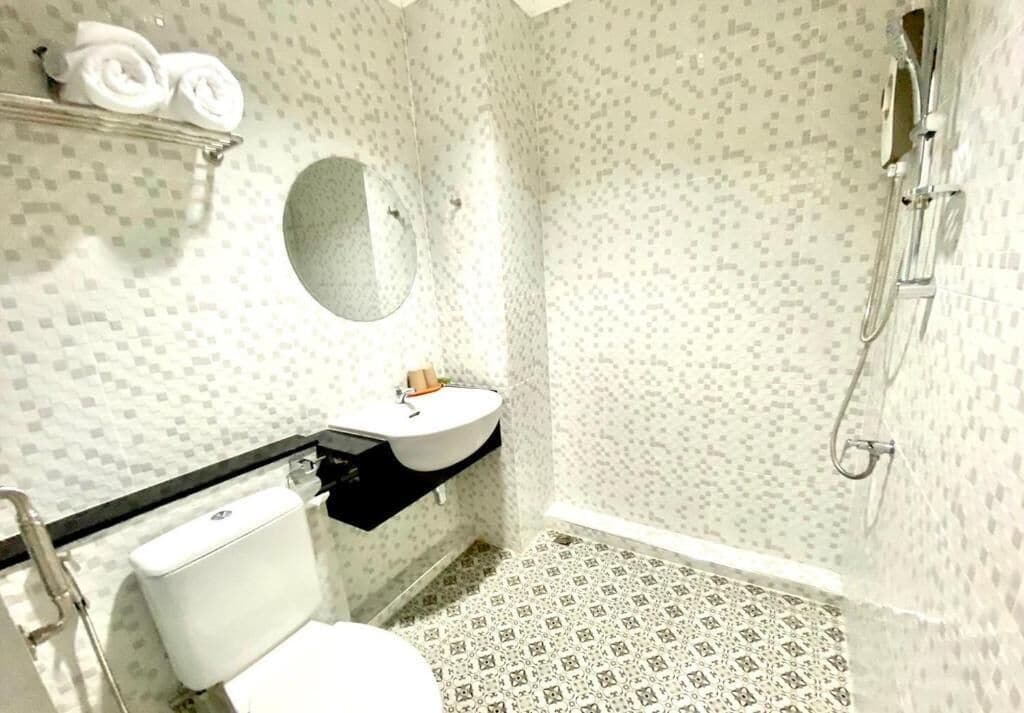 A bathroom with a toilet, sink, and shower.