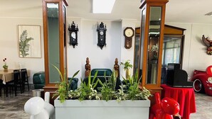 A living room with a large planter, a red chair, a white sculpture, and a vintage car model. - Chainatgrand Hotel (Chai Nat)