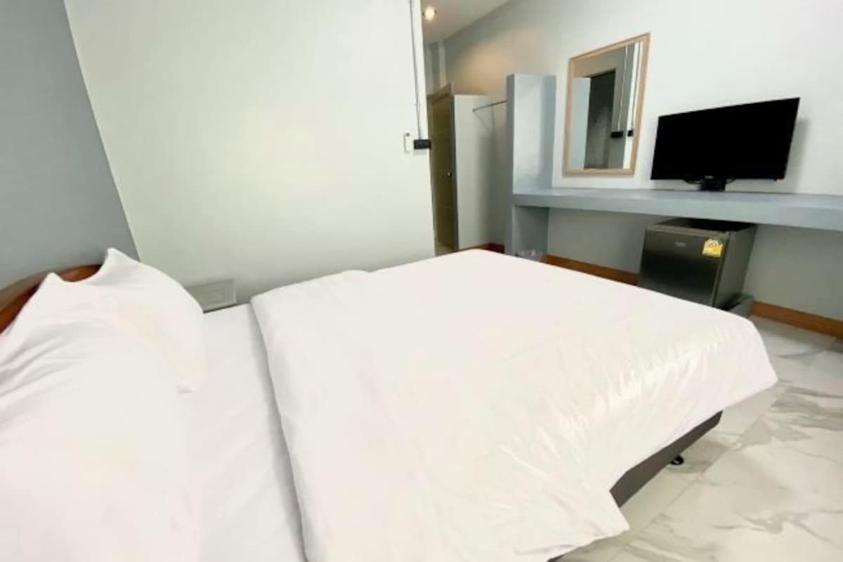 Una habitación de hotel con una cama, un televisor y un espejo en la pared.