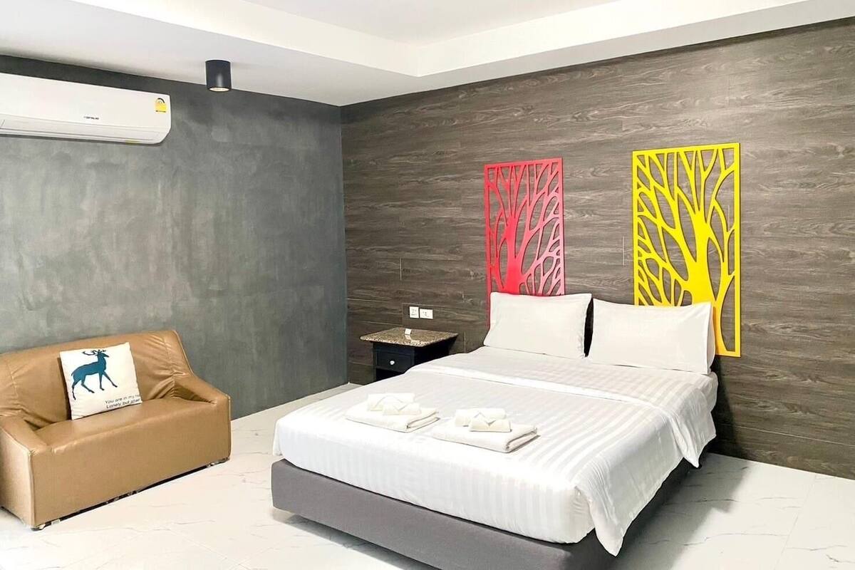 A modern bedroom with a bed, a nightstand, a sofa, and decorative panels on the wall.