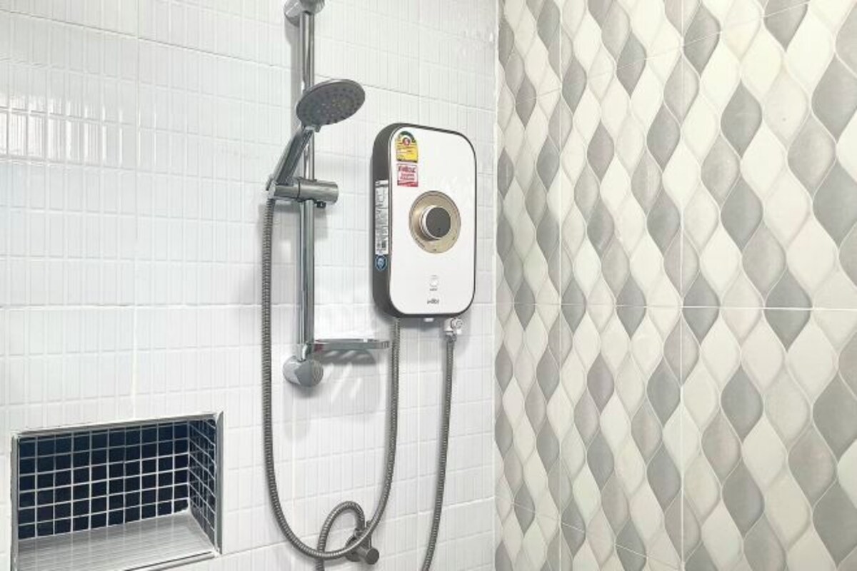 Una ducha con cabezal de ducha de mano y panel de control en la pared.