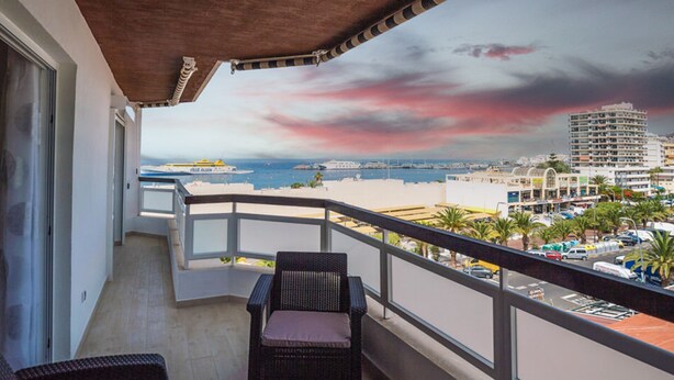 A balcony with wicker furniture, a view of the sea, and a cityscape in the background. - Spectacular apartment 100m from the seafront (Arona)