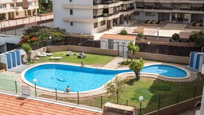 A swimming pool with two separate sections, surrounded by a well-maintained lawn and a few lounge chairs. - Spectacular apartment 100m from the seafront (Arona)