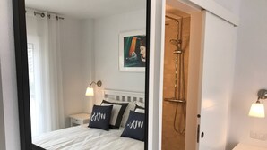 A hotel room with a bed, a nightstand, a bedside table, a shower, and a wall-mounted picture. - Spectacular apartment 100m from the seafront (Arona)